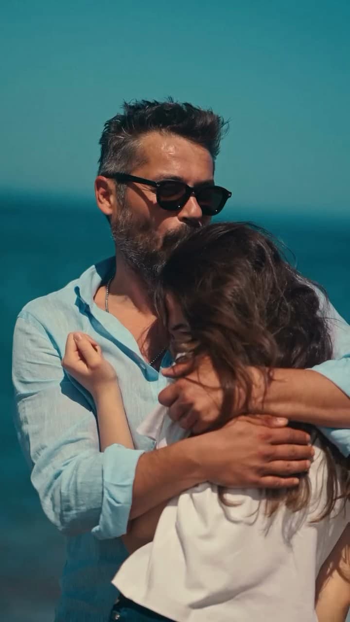 Anıl İlter in a linen shirt hugging his daughter by the sea.